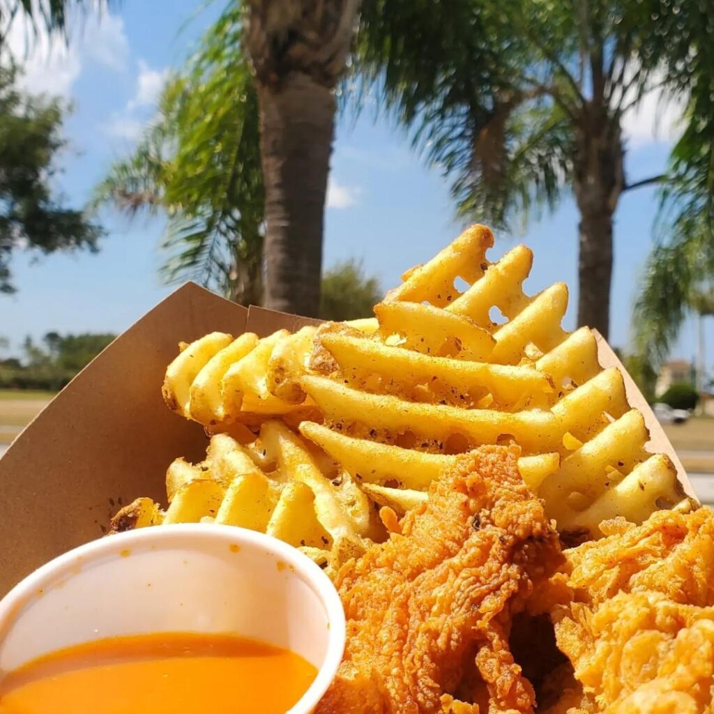Open-air outdoor seating with palm trees at The Island Chick-N-Shack in Venice Florida
